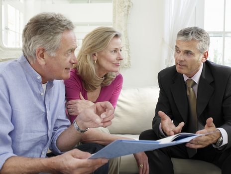 A senior citizen couple having a consultation with an male agent wearing a suit